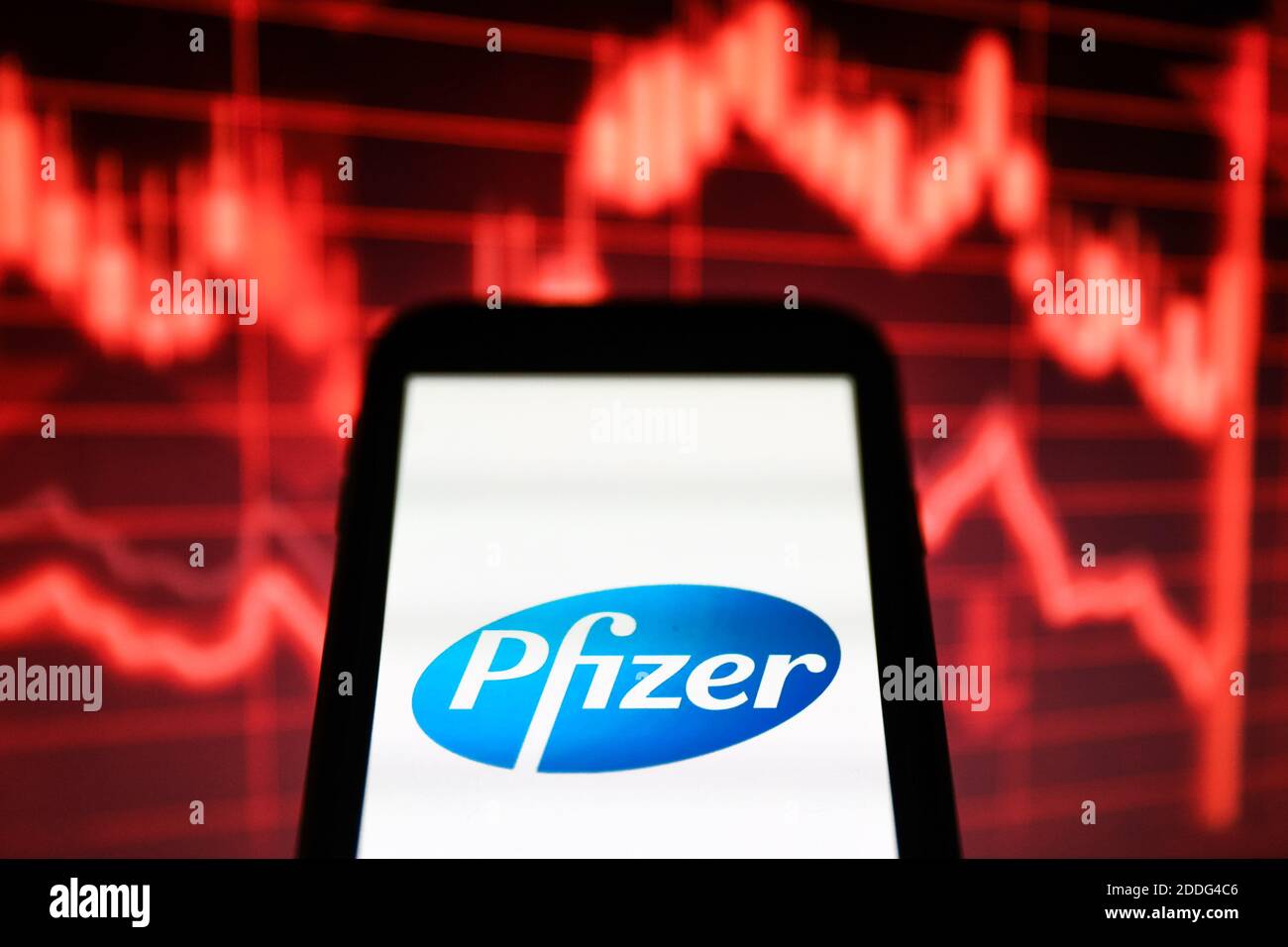In this photo illustration a Pfizer pharmaceutical company logo seen displayed on a smartphone in front of a red stock chart indicating downturn Stock Photo