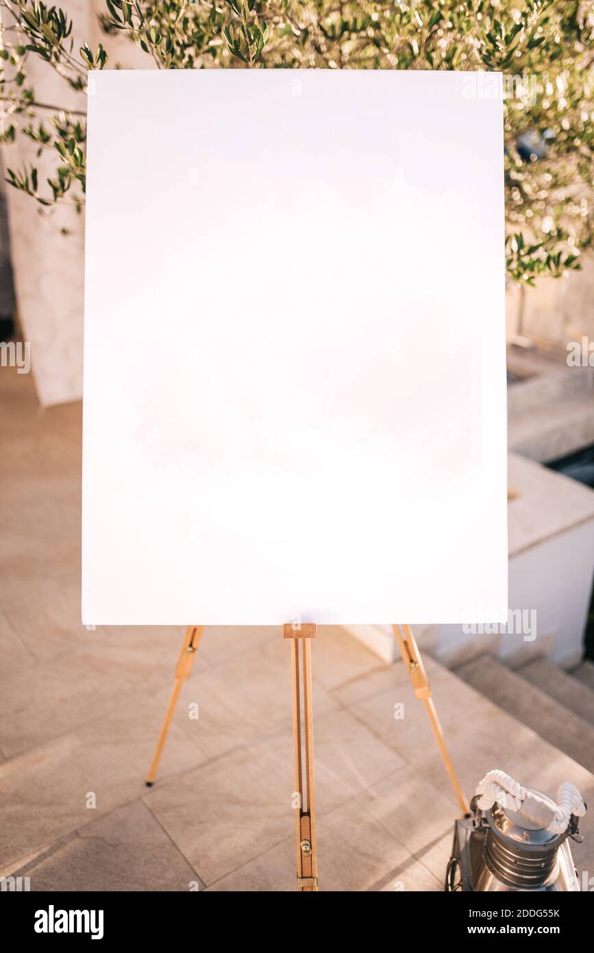 Wooden easel with white paper. Wedding day. Stock Photo