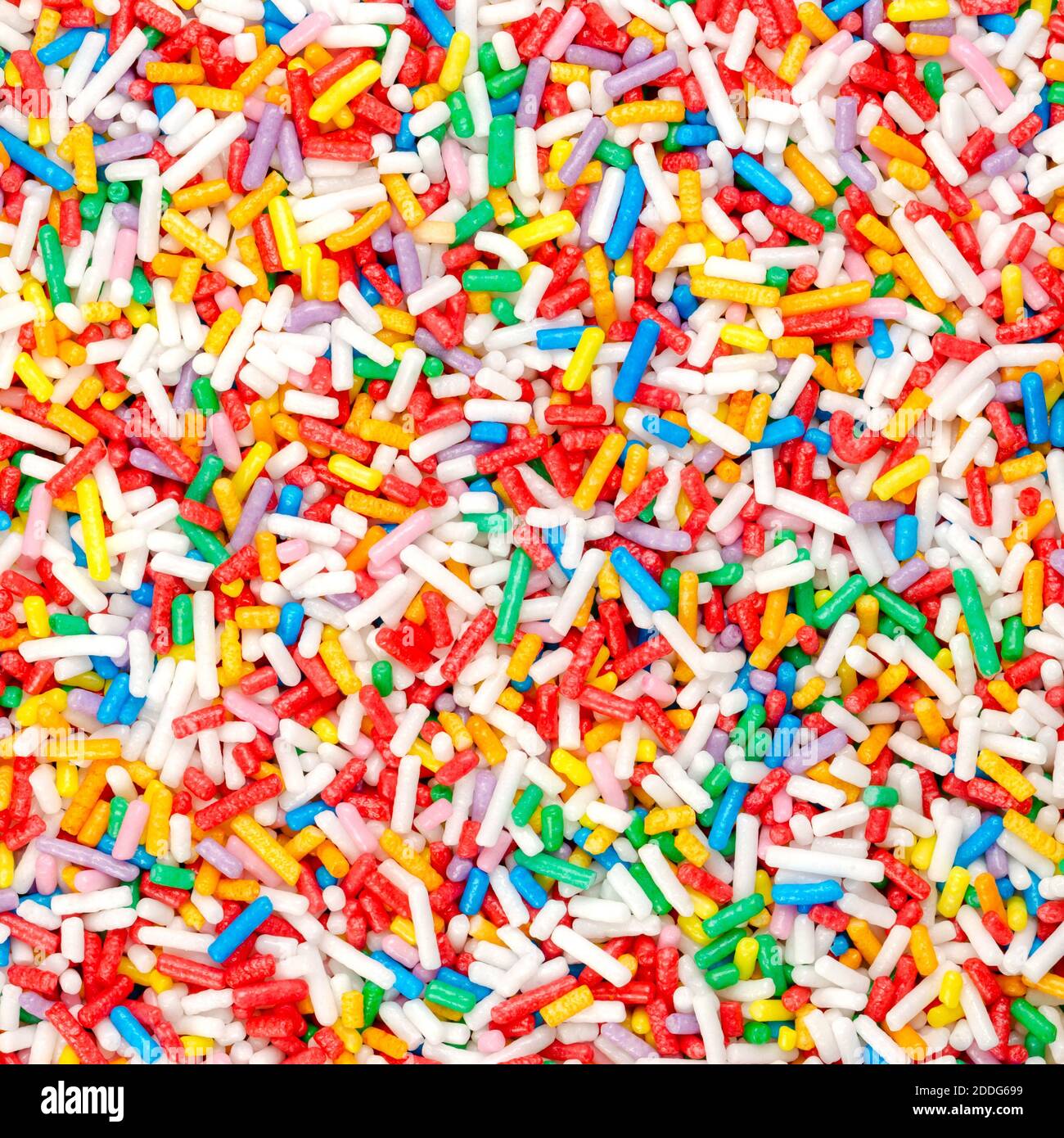 Rainbow sprinkles, square shaped background and surface. Rod-shaped colorful sugar sprinkles. Tiny candies in a variety of colors, used as a topping. Stock Photo