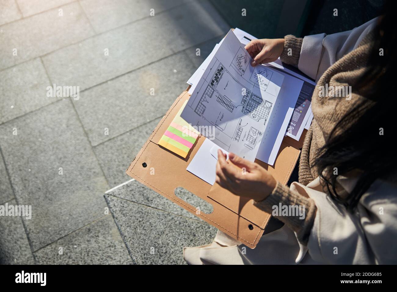 Female architect studying architectural plan on the street Stock Photo