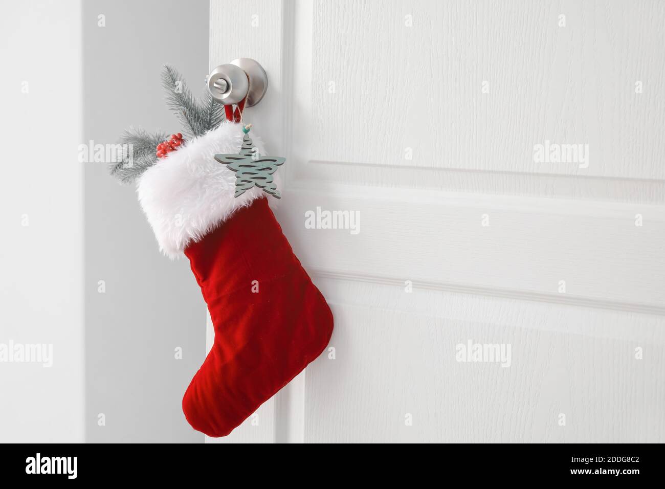 Beautiful Christmas sock hanging on white door Stock Photo - Alamy
