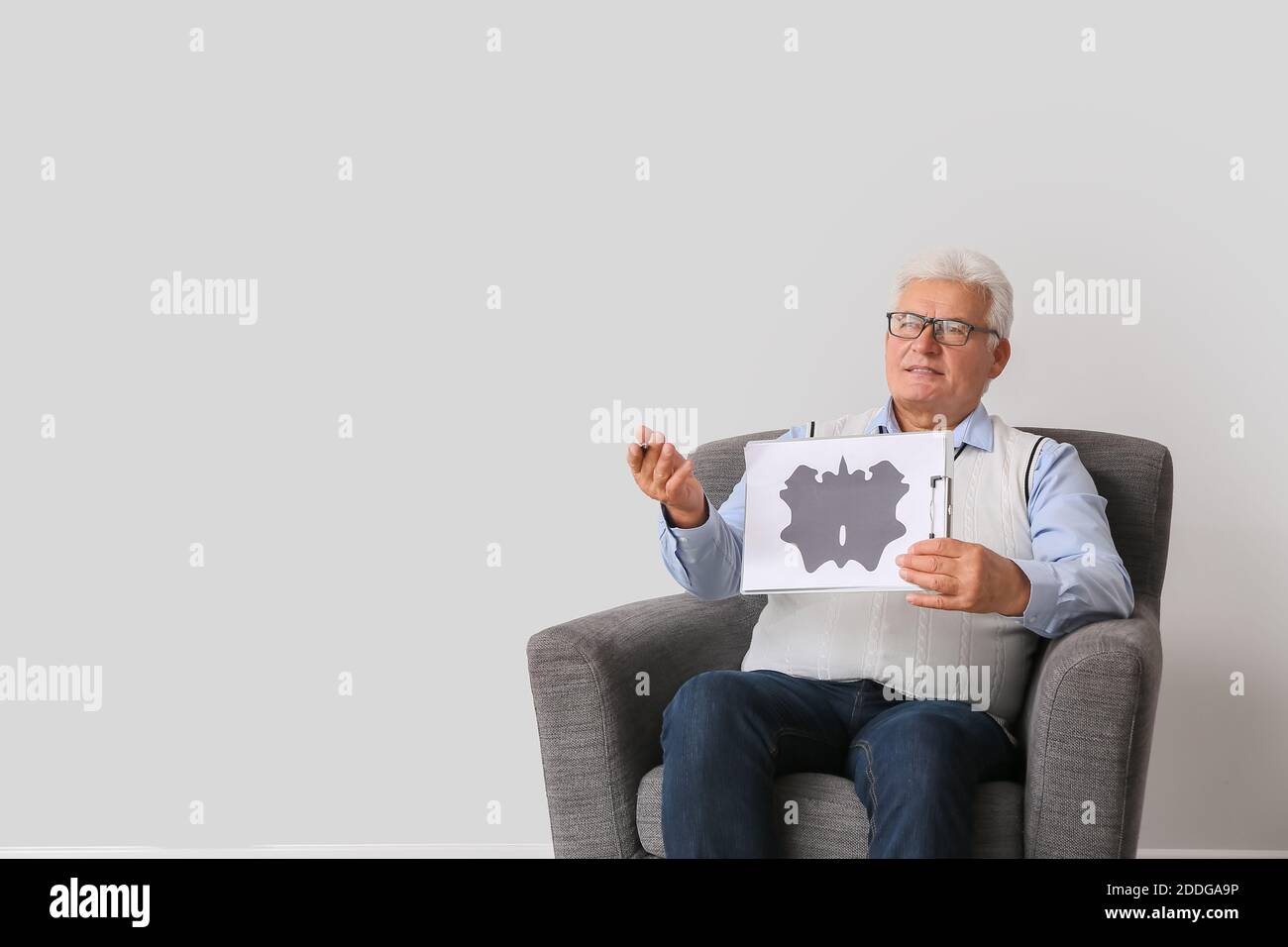 Male psychologist sitting in armchair on light background Stock Photo
