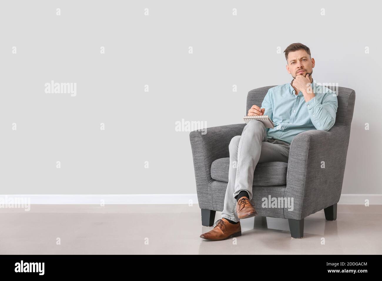 Male psychologist sitting in armchair near light wall Stock Photo Alamy