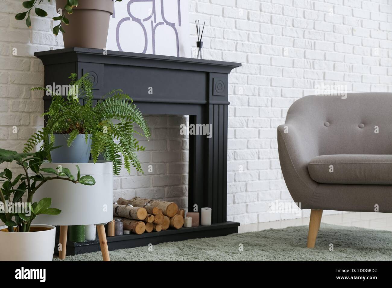Interior of modern living room with fireplace, houseplants and armchair