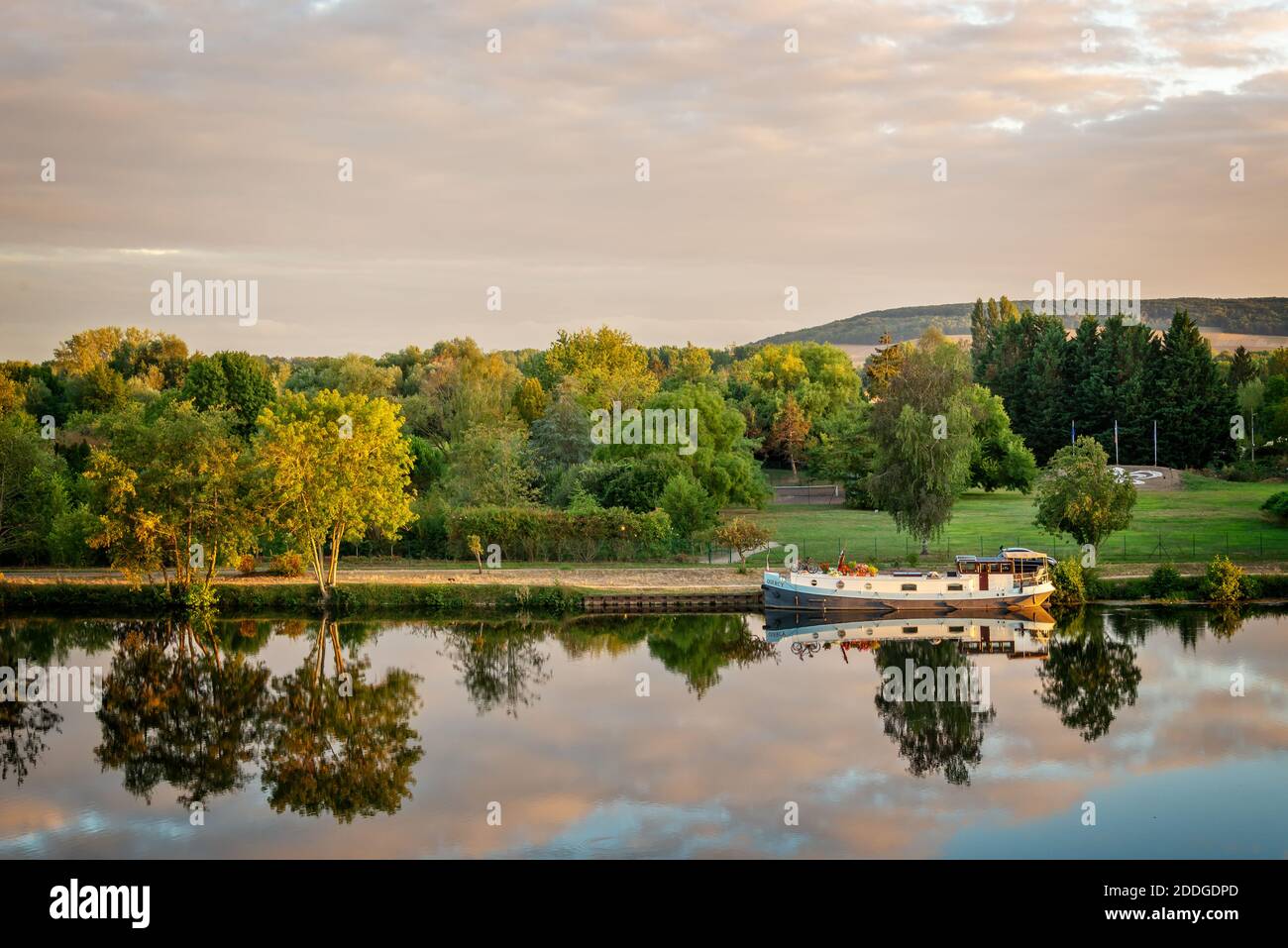 Boat on the Yonne river with reflections at sunset near Joigny in Burgundy, France. Stock Photo