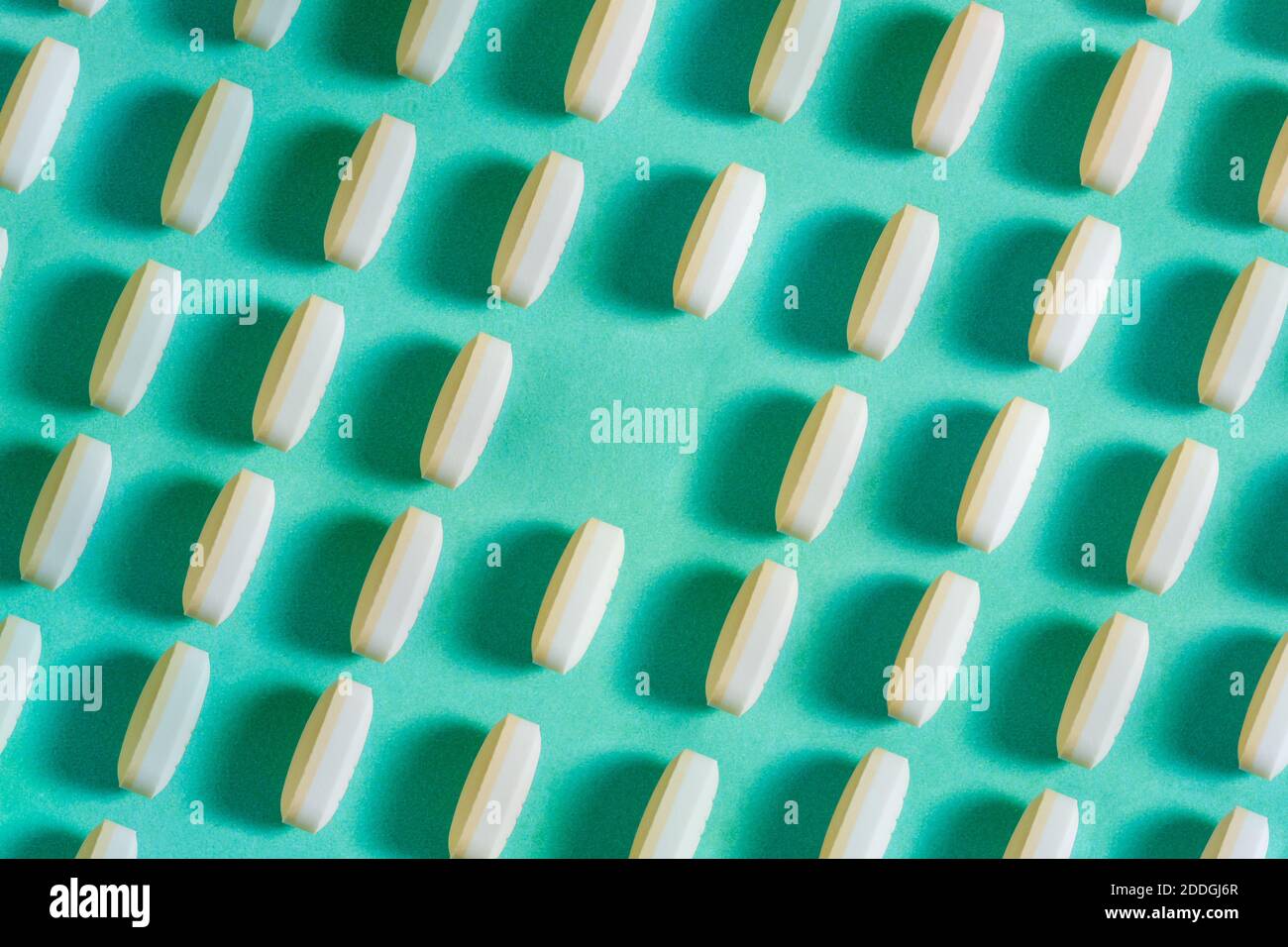 Rows of pills on a blue background. A linear pattern in which the lack of medicine leaves a clean space. Stock Photo