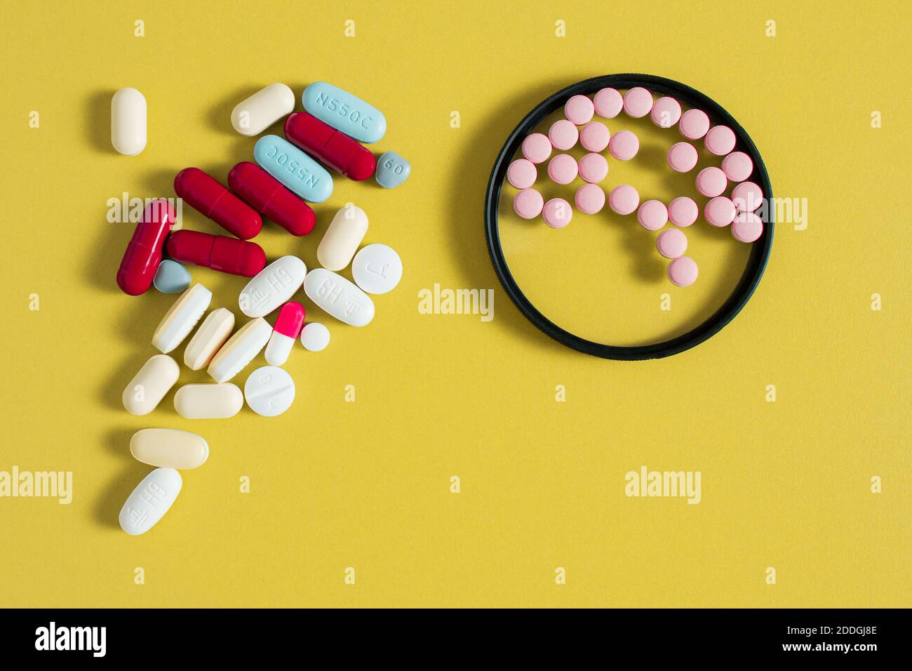 Small round pills simulate brain shape inside a circle and a bunch of different medications on a mustard-colored table. Health care concept. Stock Photo