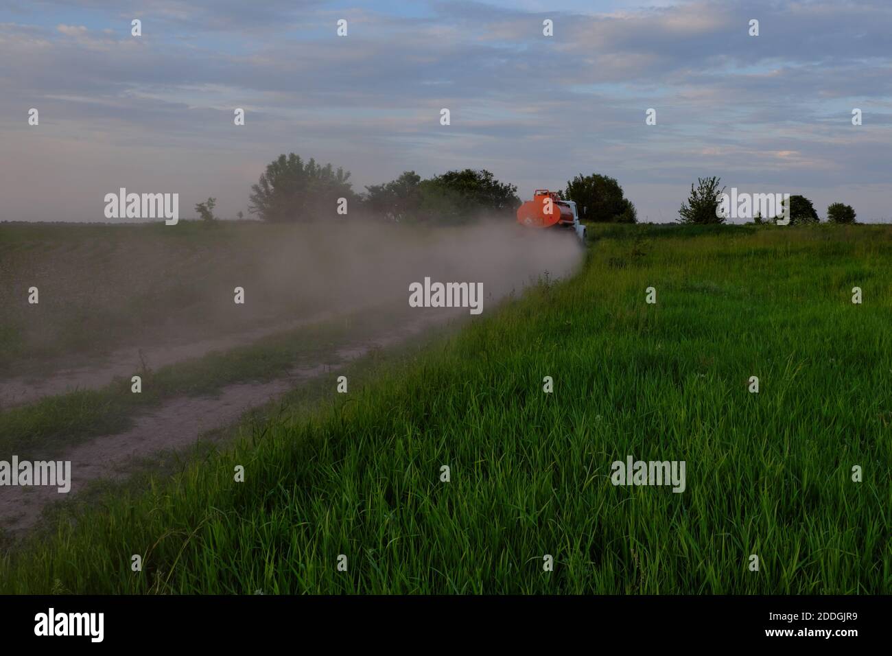 A fuel truck rushing along a dirt road leaving behind clouds of dust. Stock Photo