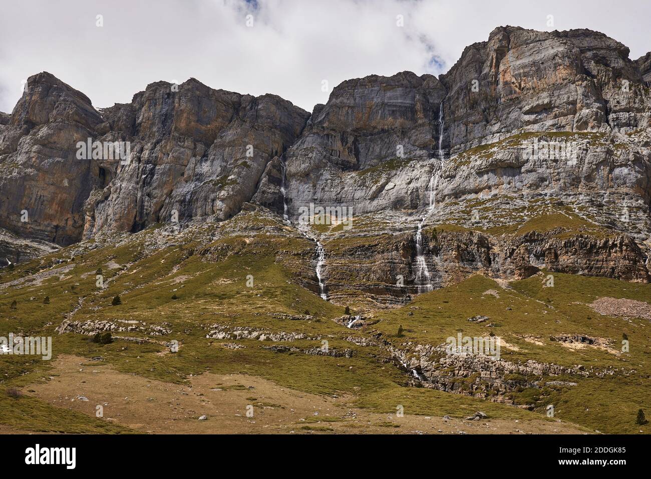 Wonderful scenery of Pyrenees mountain range and green slopes under cloudy sky in Ordesa Valley Stock Photo