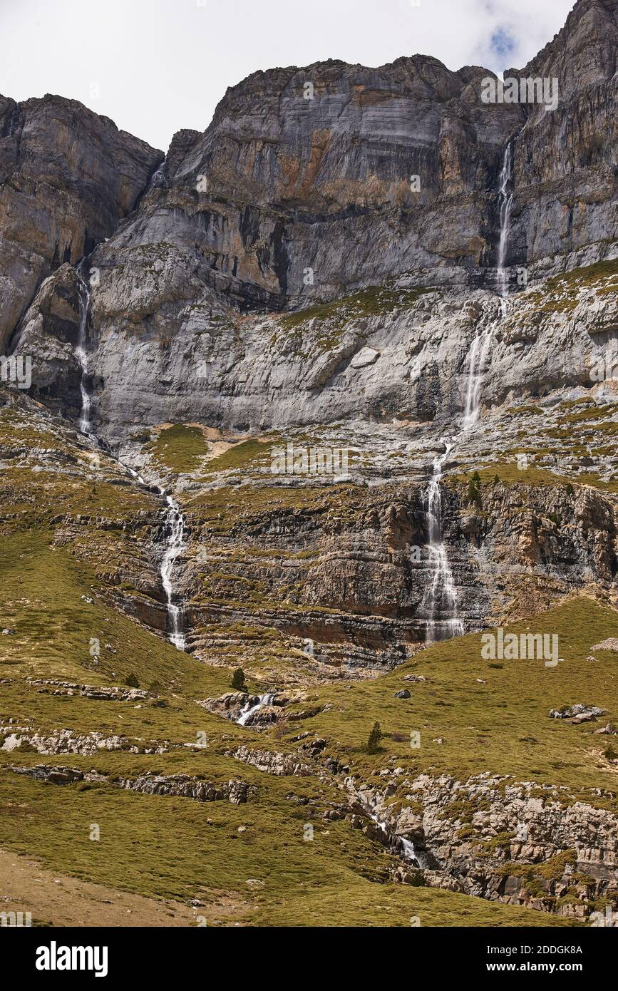 Wonderful scenery of Pyrenees mountain range and green slopes under cloudy sky in Ordesa Valley Stock Photo