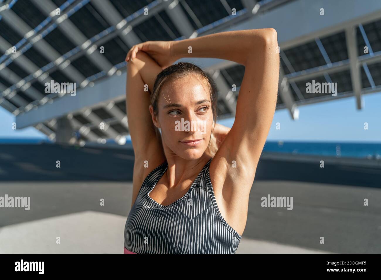 Charming female runner stretching arms while warming up before training and looking away Stock Photo