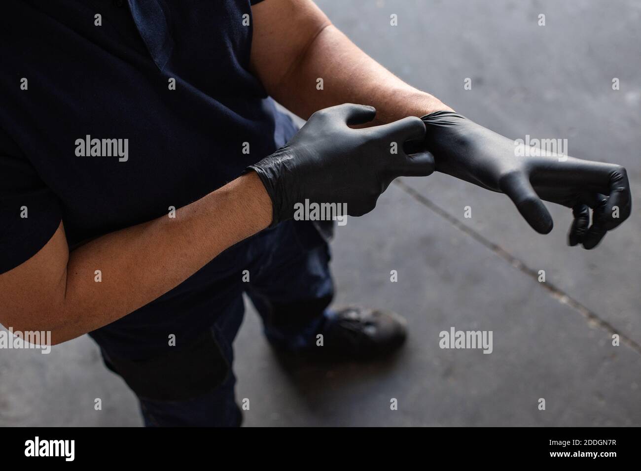 From above anonymous male employee putting on latex gloves during work in garage Stock Photo