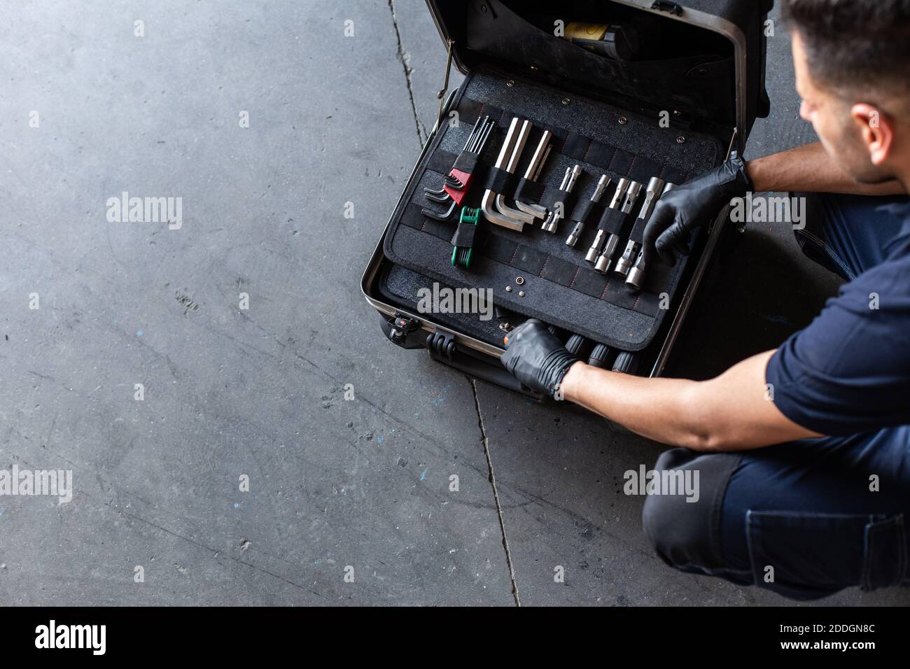 From above male technician picking screwdriver bits from tool box while working in garage Stock Photo