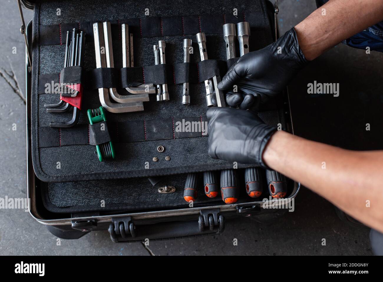 From above unrecognizable male technician picking screwdriver bits from tool box while working in garage Stock Photo