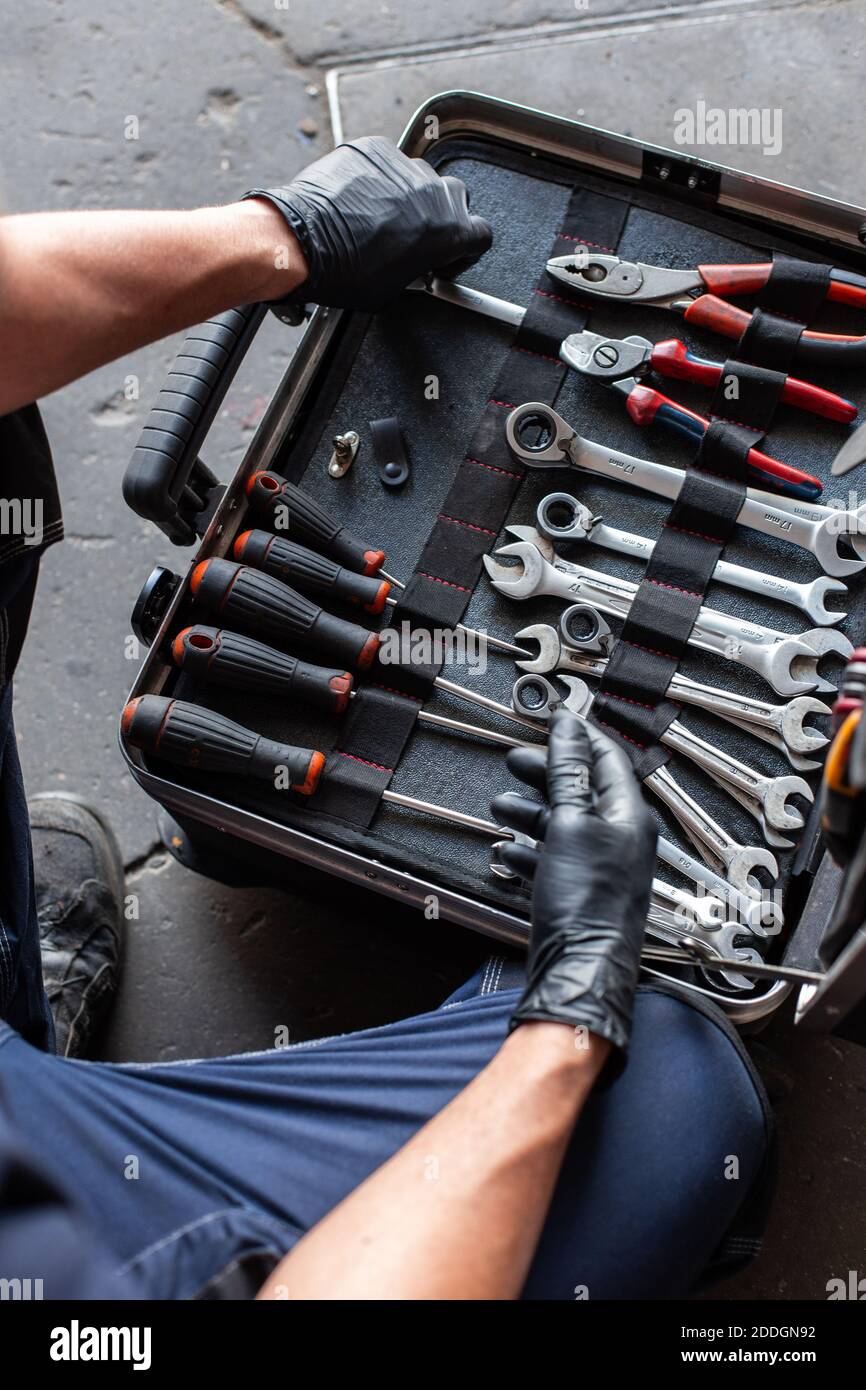 From above unrecognizable male technician picking screwdriver bits from tool box while working in garage Stock Photo
