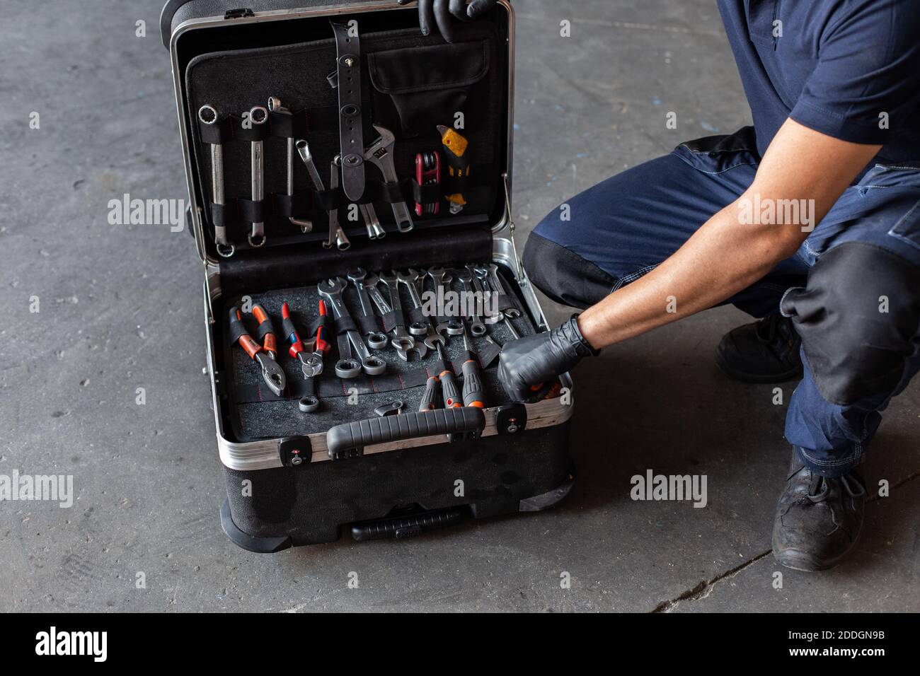 From above unrecognizable male technician picking screwdriver bits from tool box while working in garage Stock Photo