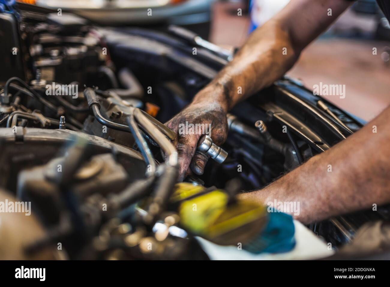 From above crop male mechanic illuminating engine with flashlight and checking motor of vehicle