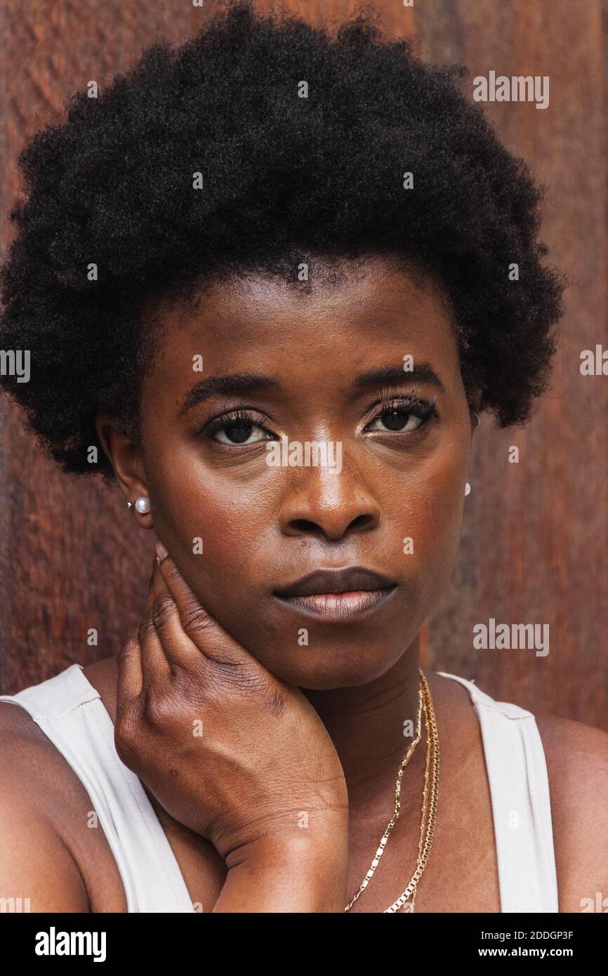 Young unhappy African American female with curly hair standing against ...