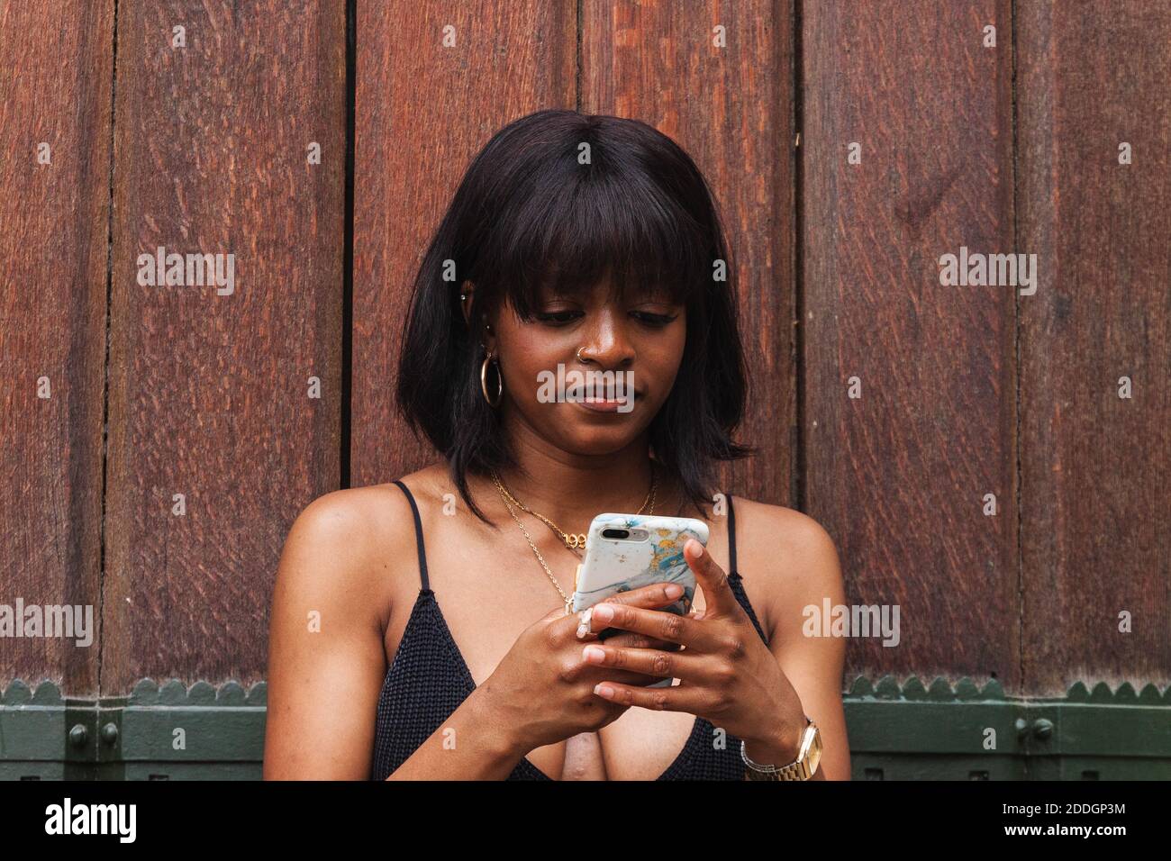 Young African American female wearing black top with decollete texting on smartphone Stock Photo