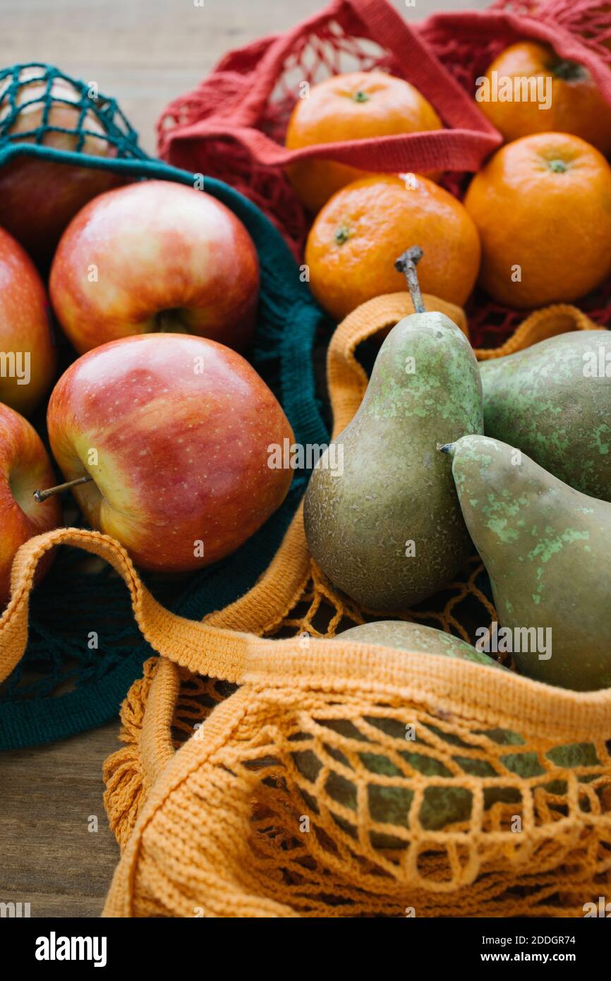 Assorted fresh fruit in cotton eco friendly sacks placed on wooden table Stock Photo