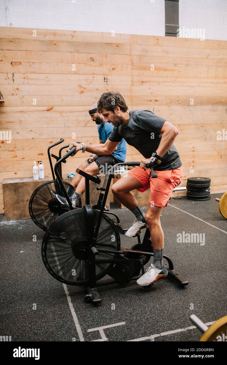 Side view of active male athletes doing exercises on air cycling