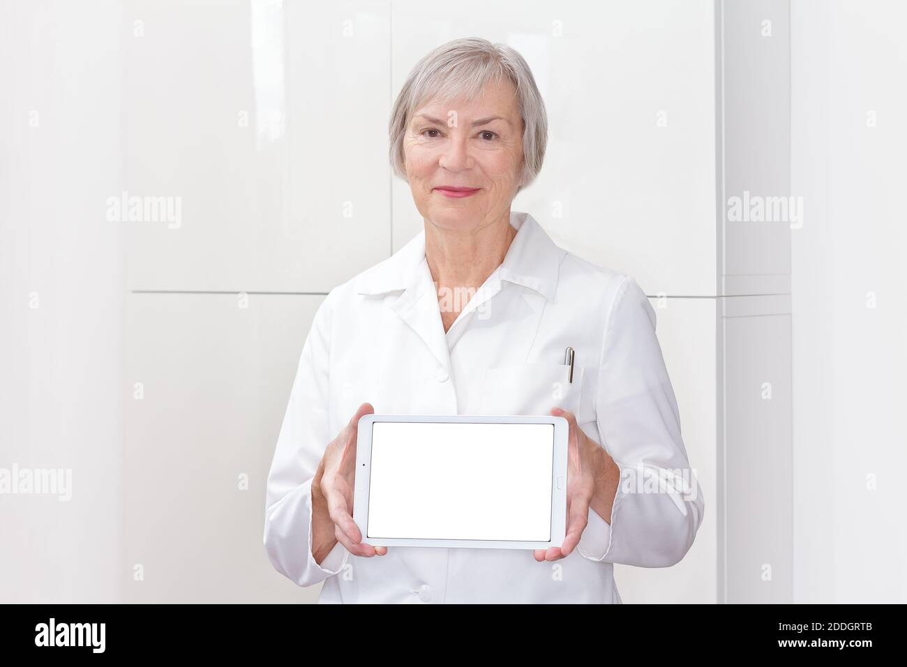 Friendly senior doctor holding a tablet computer, white copy space, m-health template. Stock Photo