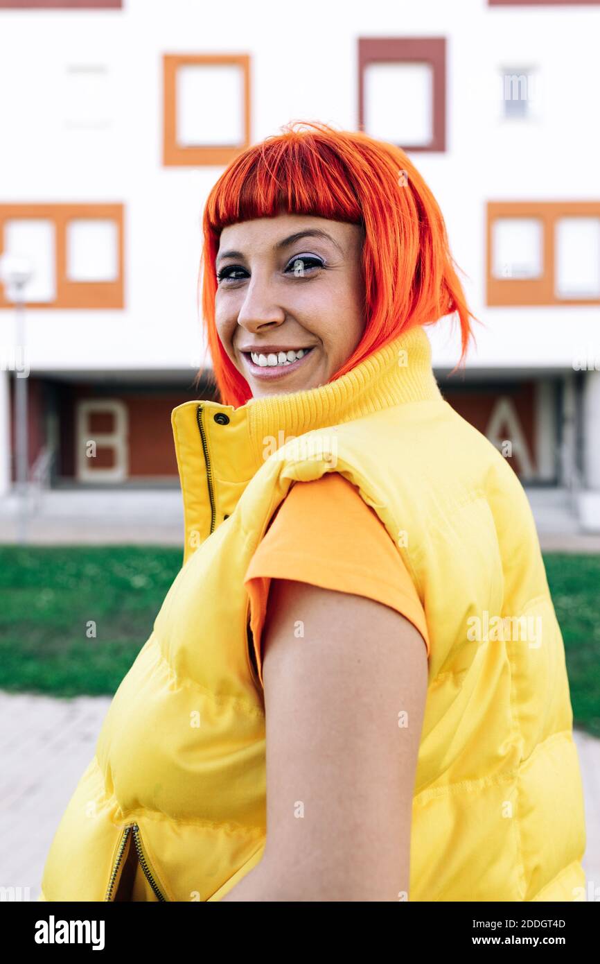Adult female with vibrant red dyed hair looking at camera on street Stock Photo