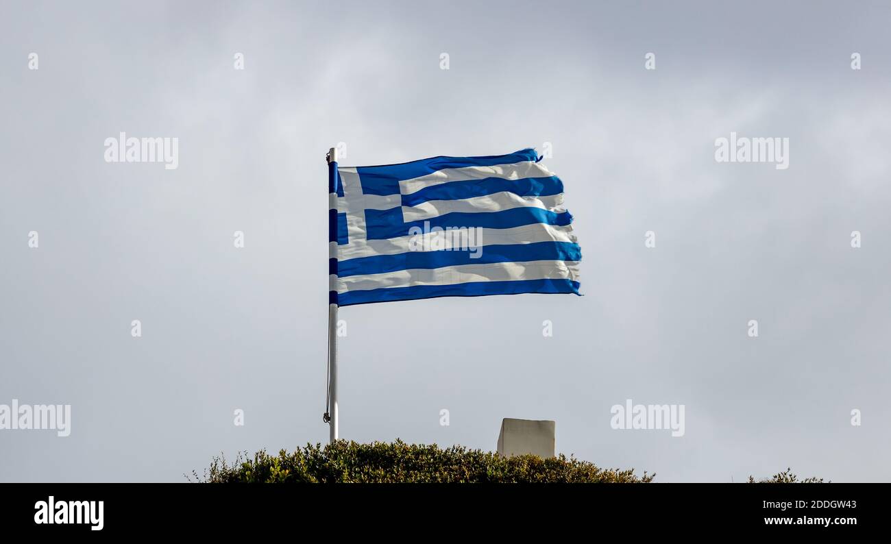Greek flag waving on pole against blue cloudy sky background, copy space. Greece national sign symbol Stock Photo