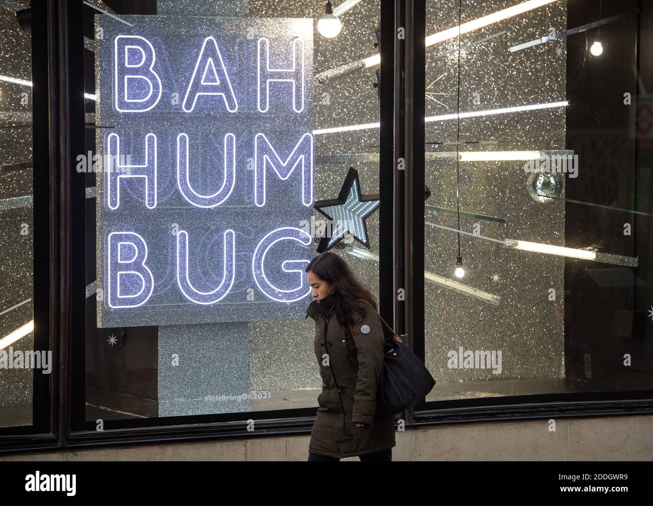 A woman passes a Christmas window display reading 'Bah Humbug', in central London, as England approaches the final week of a four week national lockdown to curb the spread of coronavirus. Stock Photo