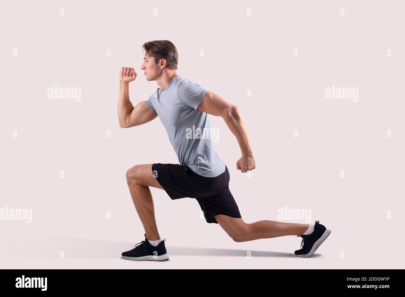 side-view-of-strong-millennial-guy-in-sportswear-doing-lunges-on-light-studio-background-2DDGWYP.jpg