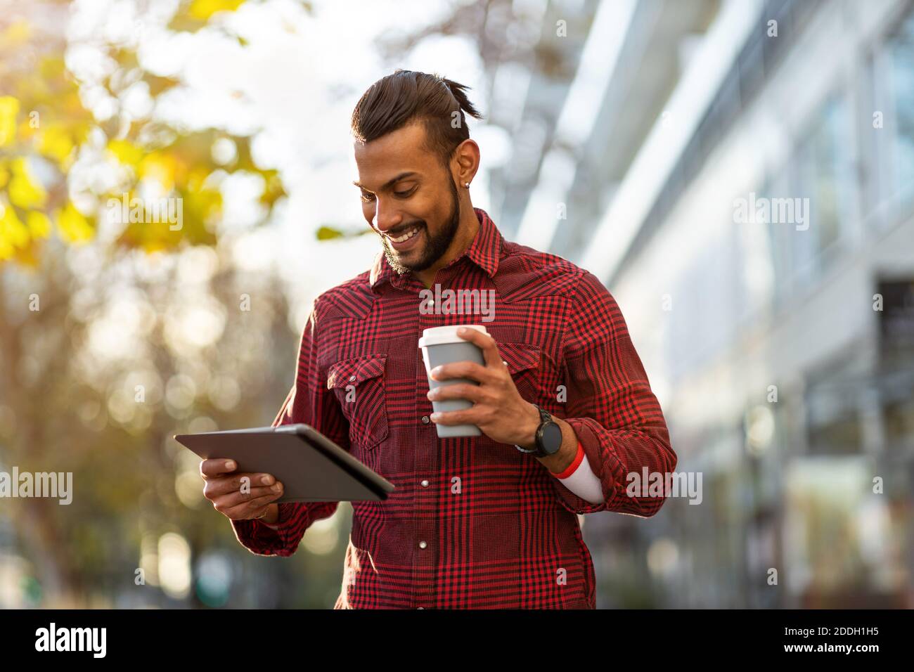 Young man using digital tablet outdoors at urban setting Stock Photo