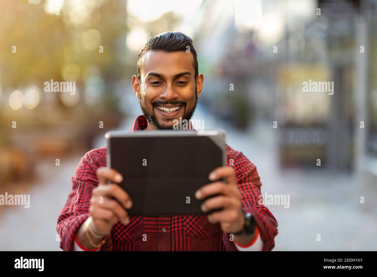 Young man using digital tablet outdoors at urban setting Stock Photo