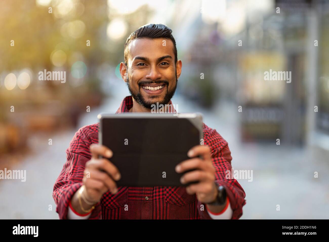 Young man using digital tablet outdoors at urban setting Stock Photo