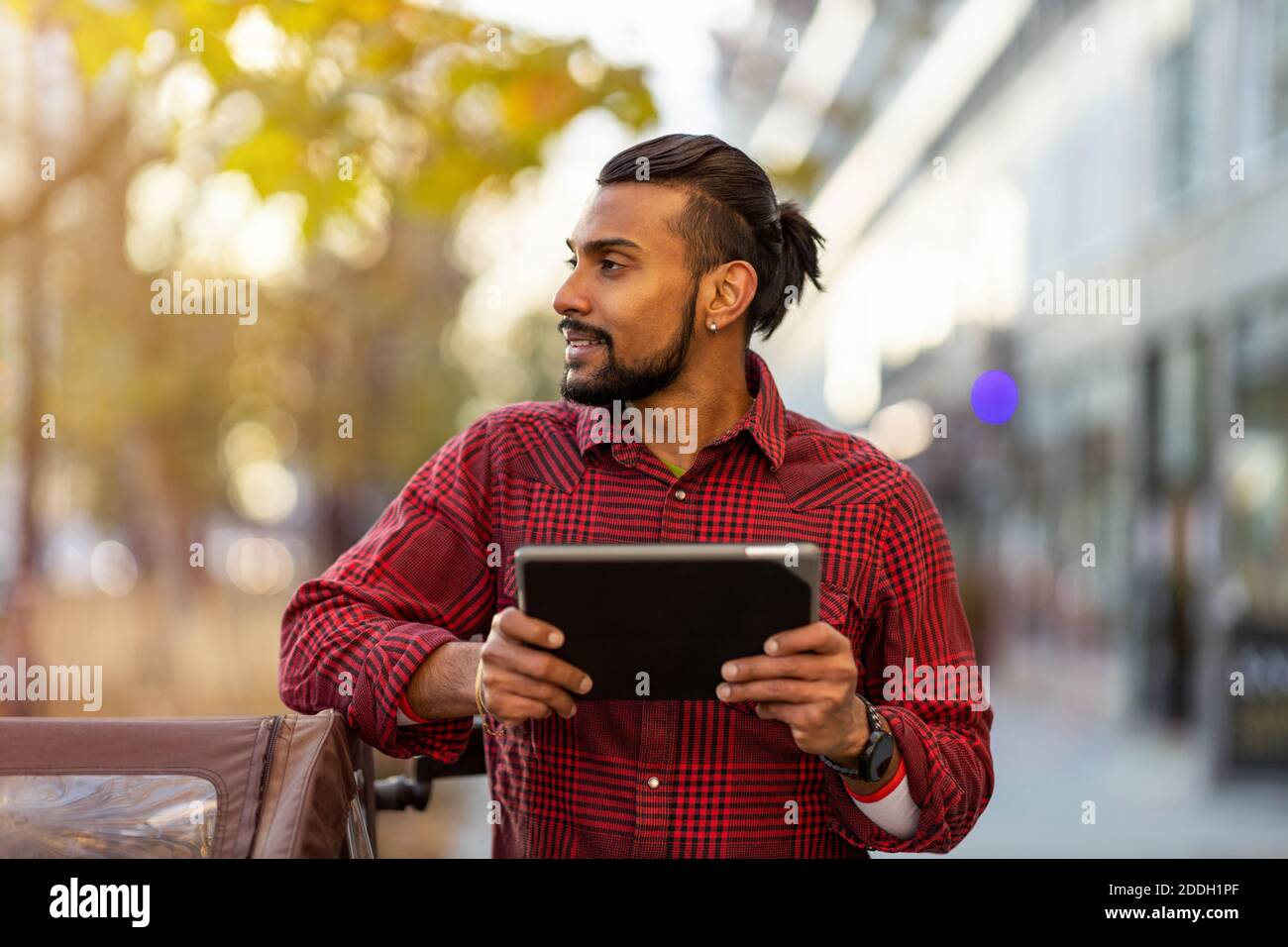 Young man using digital tablet outdoors at urban setting Stock Photo