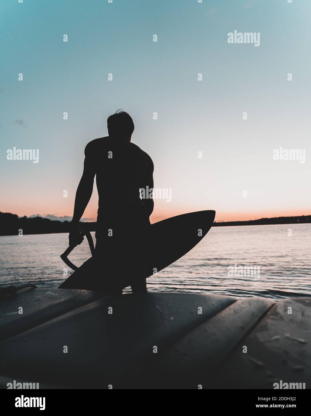 A silhouette shot of a surfer enjoying the waves during sunset Stock ...