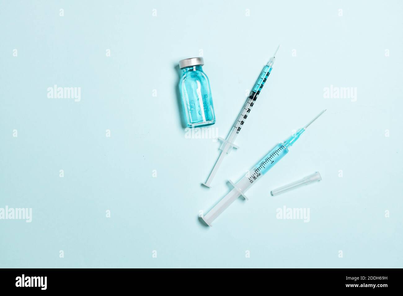 Vaccine vial, glass ampoules and a syringe with medicine on a blue ...