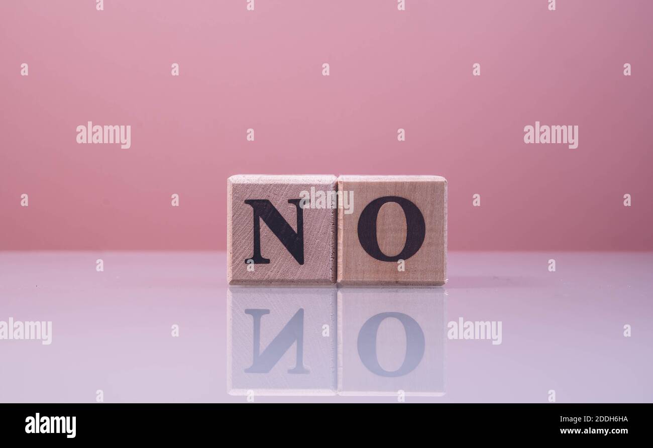 Text NO on wood cube blocks. The letters NO written on the cubes in black letters isolated on a glass surface. NO text for your desing. Stock Photo