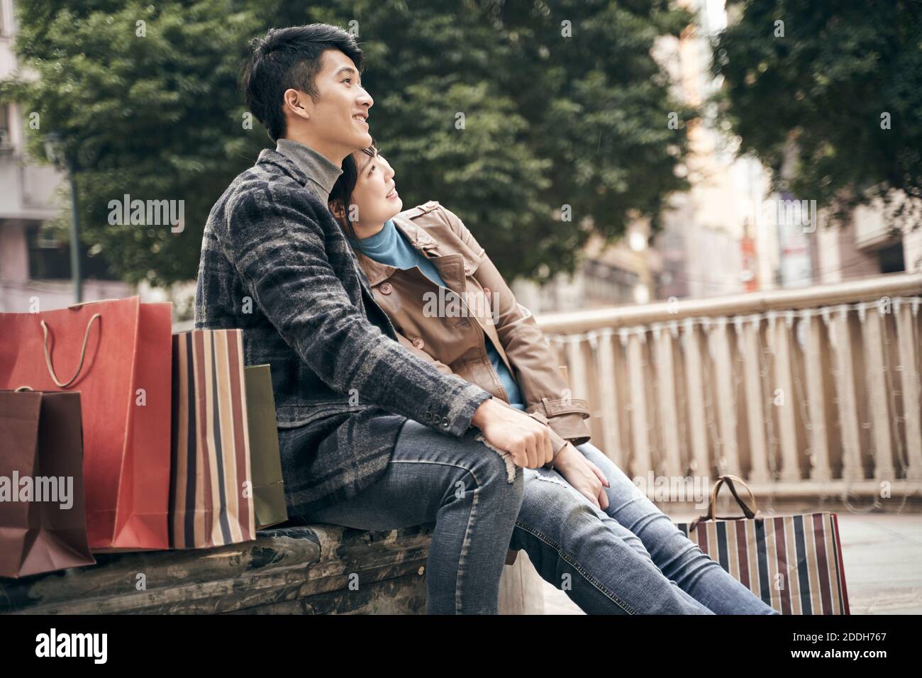 young asian couple resting relaxing outdoors while shopping in the city Stock Photo