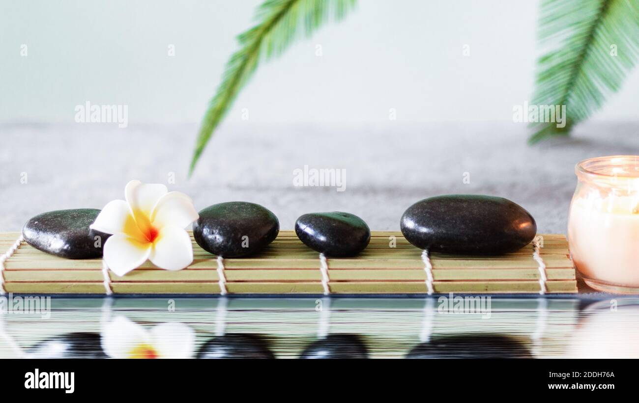 Black zen stones on grey concrete background with palm leaf near water ...