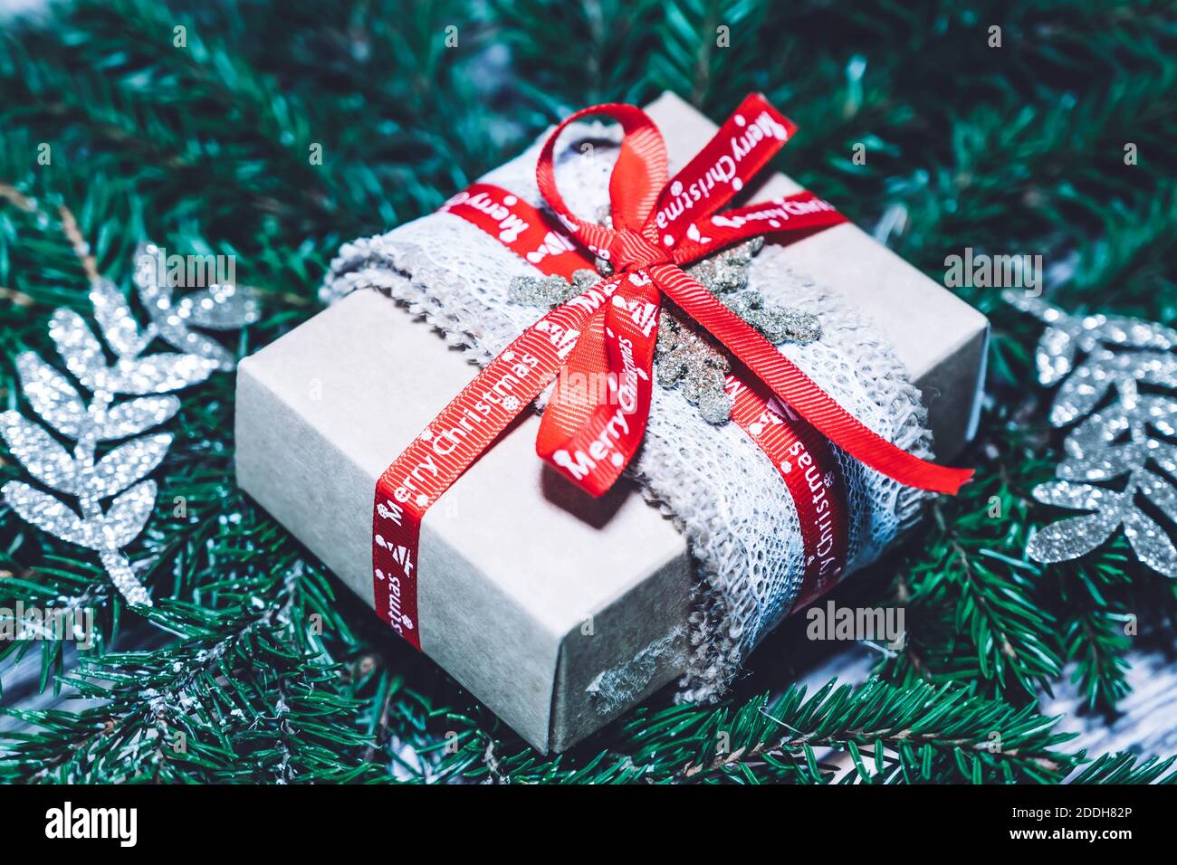 Gift box wrapped in recycled paper with ribbon bow and spruce branches ...
