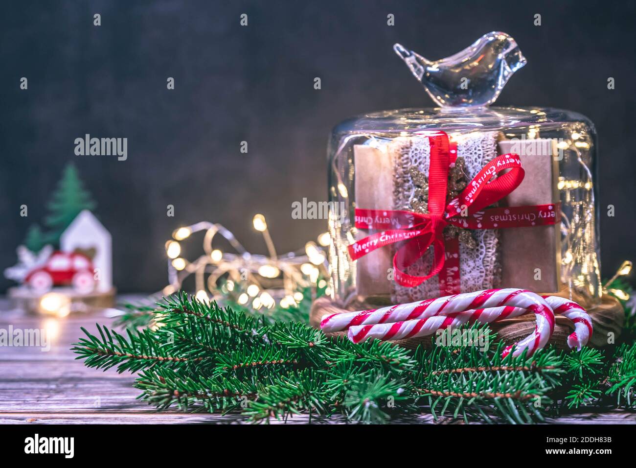 Christmas gift box in a glass cloche bell jar and christmas lights  isolated on dark background. Christmas background with copy space. Stock Photo