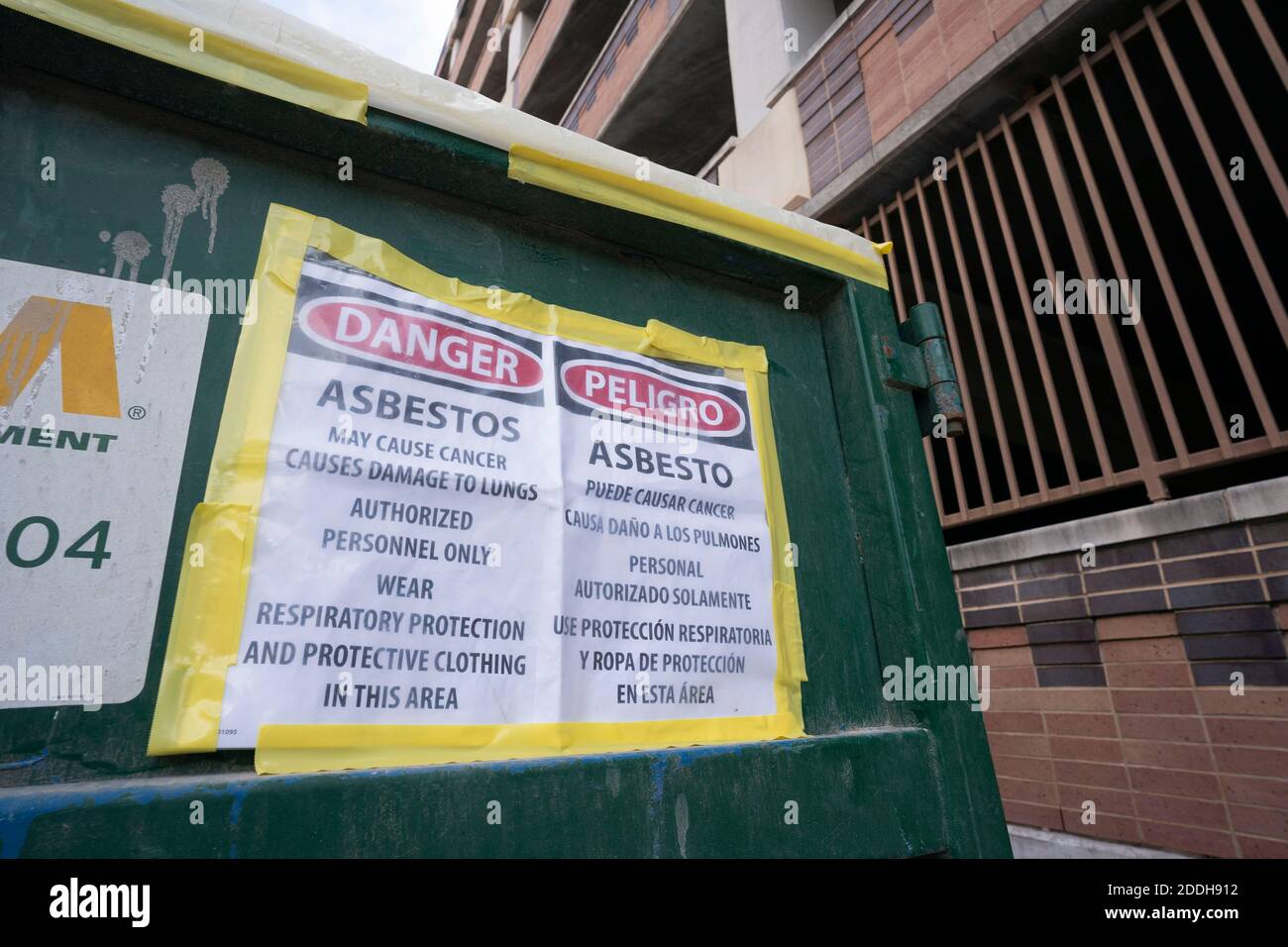 A dump container filled with asbestos-laden demolition debris sits in the alley behind a state office building in downtown Austin, Texas in November, 2020.  Renovation and construction projects continue unabated in Austin during the pandemic where other endeavors have closed shop. This dumpster adjacent to a construction site is full of asbestos, which was used in insulation, flooring and flame retardant materials in the 50's and '60's. Stock Photo