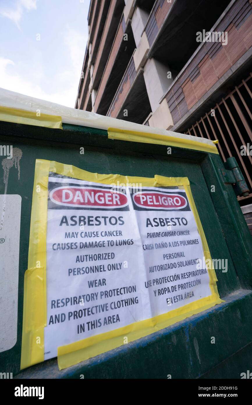 A dump container filled with asbestos-laden demolition debris sits in the alley behind a state office building in downtown Austin, Texas in November, 2020.  Renovation and construction projects continue unabated in Austin during the pandemic where other endeavors have closed shop. This dumpster adjacent to a construction site is full of asbestos, which was used in insulation, flooring and flame retardant materials in the 50's and '60's. Stock Photo