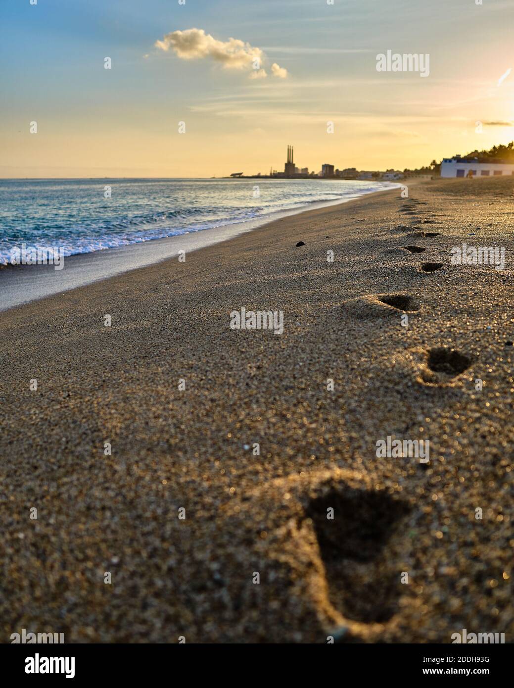 Focus on the 2nd footstep on the beach at sunset time in Badalona Spain with a fade of the landscape on the background Stock Photo