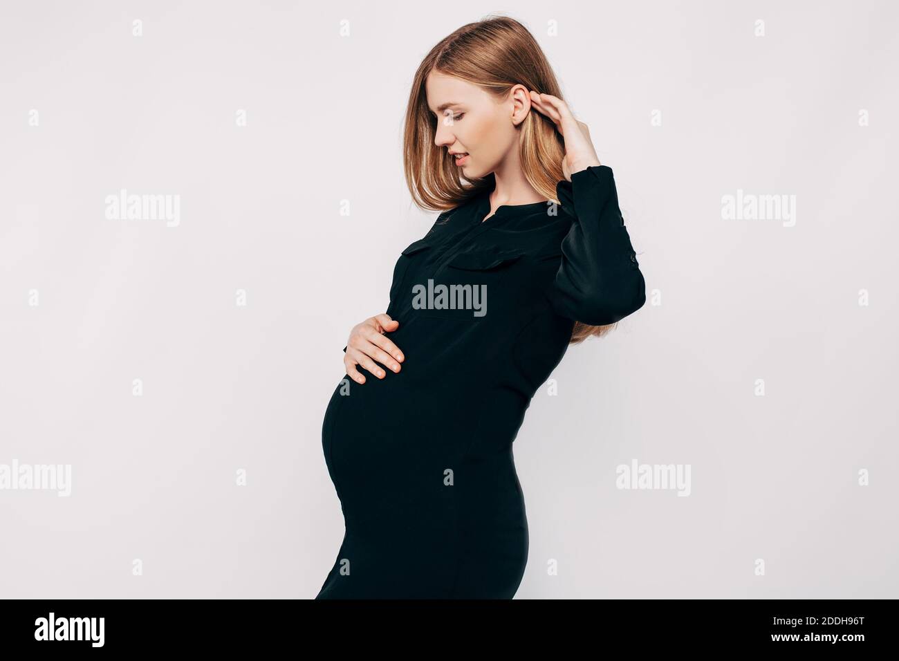 Beautiful pregnant woman in black dress posing on a white background, fashion photography pregnancy Stock Photo