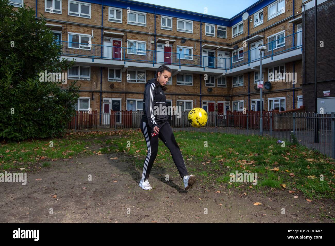 Teenage girl outside her home after school playing football after a national coronavirus lockdown stopped her playing for her Saturday football team. Stock Photo