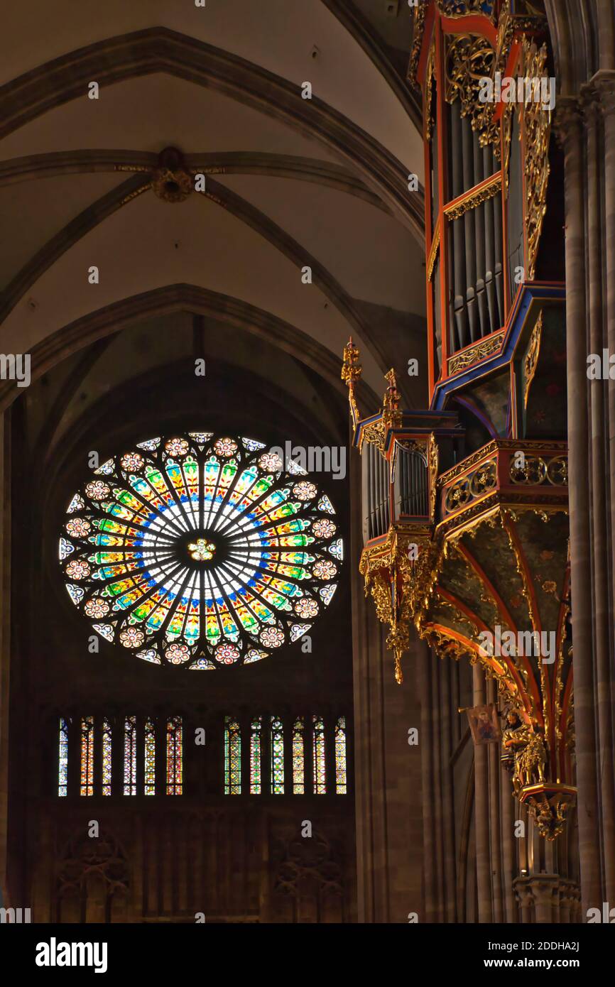 The very beautiful circular west window of Strasbourg Cathedral with the decorative organ showing on the right and some of the roof interior Stock Photo