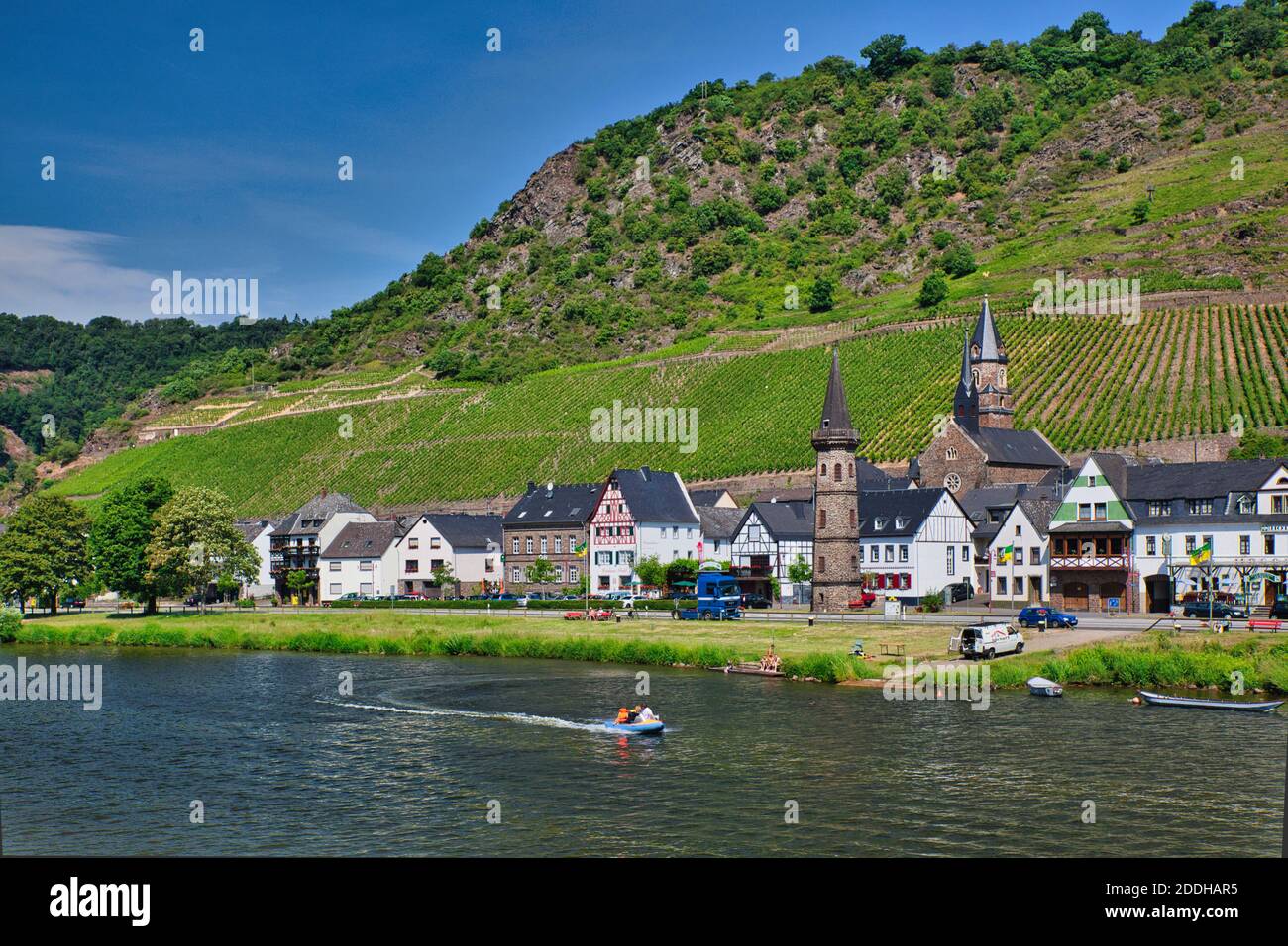 A view from the River Rhine in Germany of a townscape on the river bank with circular round tower in the foreground and green hillside slopes Stock Photo