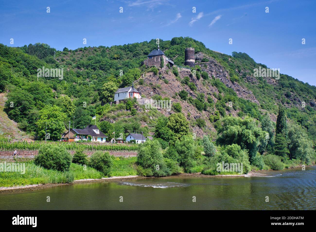 A pretty landscape viewed from the River Rhine in Germany with buildings on a hillside and a castle tower overlooking from the top. Stock Photo
