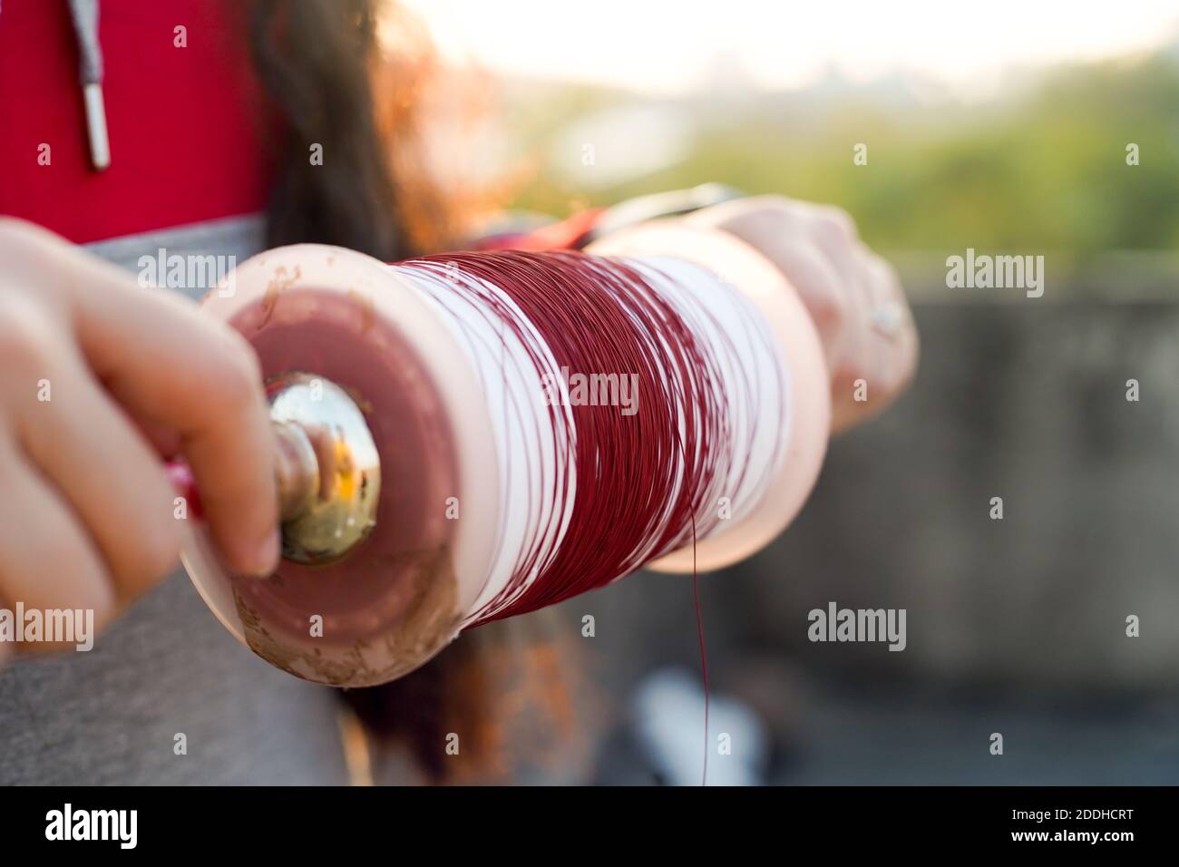 Man holding a charki phirki thread spool in the crook of his elbow and ...